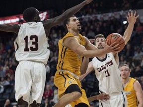 Ryerson Rams' Manny Diressa, centre, drives to the basket between Carleton Ravens Munis Tutu, left, and Cam Smythe during the second half of semifinal action in the U Sports men's basketball national championship in Halifax on Saturday, March 10, 2018. THE CANADIAN PRESS/Darren Calabrese