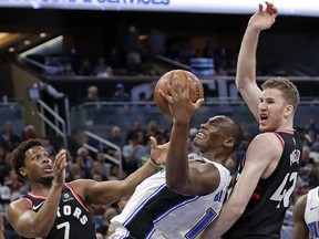 Orlando Magic's Bismack Biyombo, center, grabs a rebound between Toronto Raptors' Kyle Lowry (7) and Jakob Poeltl, right, during the second half of an NBA basketball game Wednesday, Feb. 28, 2018, in Orlando, Fla. Toronto won 117-104. (AP Photo