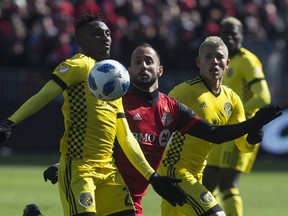 Columbus Crew defender Harrison Afful (left) chests the ball away from Toronto FC midfielder Victor Vazquez (centre left) during first half MLS action in Toronto on Saturday, March 3, 2018. THE CANADIAN PRESS/Chris Young