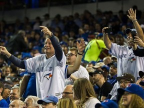 Toronto Blue Jays fans interact with the Blue Jays mascot during a break in the action against the New York Yankees at the Rogers Centre in Toronto, Ont. on Thursday, March 29, 2018.