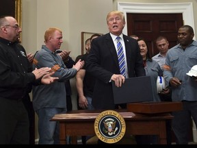 U.S. President Donald Trump, centre, stands up to walk out of the Roosevelt Room at the White House in Washington, Thursday, March 8, 2018, following an event where he signed two proclamations, one on steel imports and the other on aluminum imports. (AP Photo/Susan Walsh)