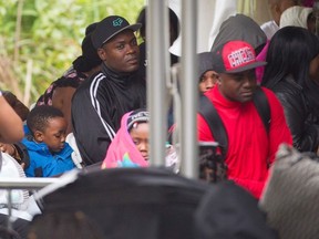 (FILES) This file photo taken on August 6, 2017 shows refugees waiting to be processed by the Royal Canadian Mounted Police after crossing the Canada/US border near Hemmingford, Quebec. Canada said November 21, 2017 it is ready to deal with an influx of asylum seekers after Washington announced it would soon end protections granted to Haitians following a deadly 2010 earthquake. "We've been planning for every conceivable scenario," Public Safety Minister Ralph Goodale said.Some 59,000 Haitian immigrants in the United States will lose their Temporary Protected Status (TPS) in 18 months, the US announced on Monday, opening the door for their potential repatriation to their desperately poor home country.