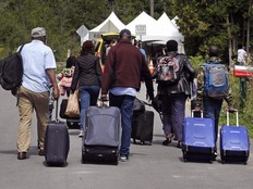 A family from Haiti approach a tent in Saint-Bernard-de-Lacolle, Quebec, stationed by Royal Canadian Mounted Police, as they haul their luggage down Roxham Road in Champlain, N.Y., Monday, Aug. 7, 2017. (AP Photo/Charles Krupa)