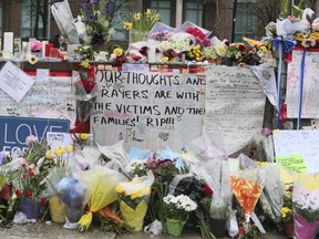 A steady stream of people stop to drop off flowers and read handwritten notes at a memorial wall at Yonge St and Finch Ave. on Wednesday April 25, 2018 after the deadly van attack in North York.