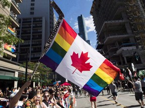 A man holds a flag on a hockey stick during the Pride parade in Toronto on June 25, 2017.