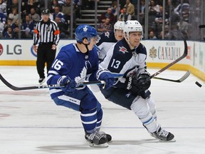 Brandon Tanev #13 of the Winnipeg Jets flips a puck away from Mitchell Marner #16 of the Toronto Maple Leafs during an NHL game at the Air Canada Centre on March 31, 2018 in Toronto, Ontario, Canada. The Jets defeated the Maple Leafs 3-1.