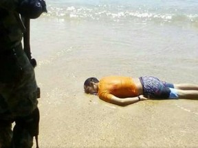 A soldier stands over the body of a man found shot to death on a popular Acapulco beach.