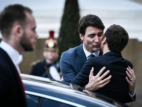 French President Emmanuel Macron (L) hugs Canadian Prime Minister Justin Trudeau as he escorts him following their meeting at the Elysee Palace in Paris, on April 16, 2018.