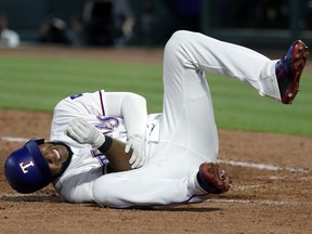 Texas Rangers' Elvis Andrus rolls on the ground by home plate holding his right elbow after being hit by a pitch from Los Angeles Angels' Keynan Middleton in the ninth inning of a baseball game in Arlington, Texas, Wednesday April 11, 2018. Andrus is out 6-8 weeks with a fractured elbow. (AP Photo/Tony Gutierrez)