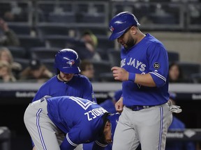 Toronto Blue Jays designated hitter Kendrys Morales, right, crosses home plate as Teoscar Hernandez pulls off his shin guard after taking a walk with the bases loaded against the New York Yankees during the fifth inning of a baseball game, Friday, April 20, 2018, in New York. (AP Photo/Julie Jacobson) ORG XMIT: NYJJ117