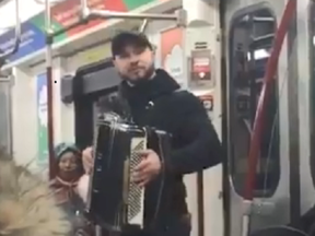A local busker with accordion jumps from subway car to subway car playing 'Despacito.'