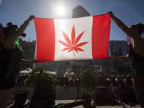Two people hold a modified design of the Canadian flag with a marijuana leaf in in place of the maple leaf during the "4-20 Toronto" rally in Toronto, April 20, 2016.  THE CANADIAN PRESS/Mark Blinch
