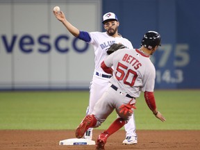 Devon Travis of the Toronto Blue Jays turns a double play in the tenth inning during MLB game action as Mookie Betts  of the Boston Red Sox slides into second base at Rogers Centre on April 24, 2018 in Toronto. (Tom Szczerbowski/Getty Images)