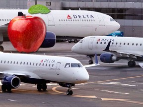 In this Jan. 8, 2018, file photo a Delta Connection Embraer 175 aircraft, foreground, taxis to a gate at Logan International Airport in Boston.