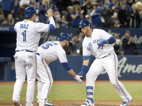 Toronto Blue Jays' Justin Smoak, right, is greeted at home plate by teammates Aledmys Diaz and Russell Martin after he hit a grand slam against the New York Yankees in the eighth inning of their American League MLB baseball game in Toronto on Sunday April 1, 2018. THE CANADIAN PRESS/Fred Thornhill