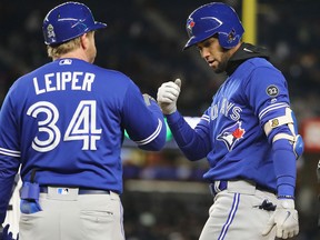 Lourdes Gurriel Jr. of the Toronto Blue Jays is congratulated by first base coach Tim Leiper after he hit an RBI single against the New York Yankees at Yankee Stadium on April 20, 2018