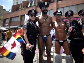 Revellers pose for a photos with police officers at the annual Pride Parade in Toronto on Sunday, July 3, 2016. The group behind Toronto's pride parade wants police to withdraw a bid to take part in the event this year.