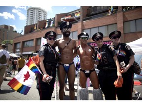 Revellers pose for a photos with police officers at the annual Pride Parade in Toronto on Sunday, July 3, 2016.
