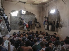 Suspected Islamic State members sit inside a small room in a prison south of Mosul, Tuesday, July 18, 2017. Hundreds of suspected Islamic State members swept up by Iraqi forces in Mosul are being held in a cramped and stifling prison just outside the city. (AP Photo/Bram Janssen)