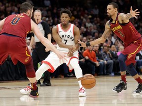 Toronto Raptors' Kyle Lowry passes the ball between Cleveland Cavaliers' Kevin Love and George Hill during an NBA Game on March 21, 2018