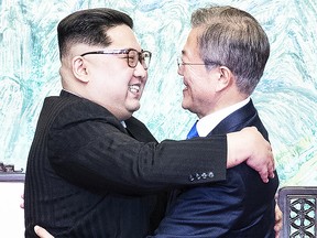 North Korea's leader Kim Jong Un, left, embraces South Korean President Moon Jae-in, right, at the Military Demarcation Line that divides their countries ahead of their meeting at the official summit Peace House building at the truce village of Panmunjom on April 27, 2018. (Getty)