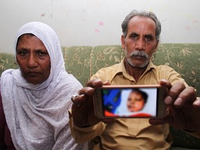 Yaqub Masih, shows a blurred picture of his daughter Asma Yaqub who was set on fire, with his wife in Sialkot, Pakistan, Monday, April 23, 2018. Pakistani official says police have arrested a Muslim man on charges of burning their daughter, a minority Christian woman, to death for refusing his marriage offer. (AP Photo/Shahid Ikram)