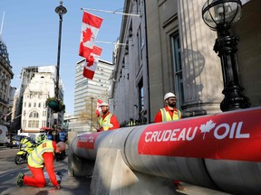 Demonstrators use a mock oil pipeline to block the entrance to the Canadian Embassy in London on Wednesday, April 18, 2018, as they protest against the Trans Mountain oil pipeline from Alberta's oil sands to the Pacific Ocean. (Tolga Akmen/AFP/Getty Images)