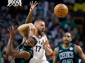 Boston Celtics' Kadeem Allen, left, and Toronto Raptors' Jonas Valanciunas (17) battle for a rebound in Boston, Saturday, March 31, 2018. (AP Photo/Michael Dwyer)