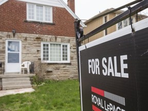 In this file photo, a for sale sign sits on the yard of a home in Toronto.