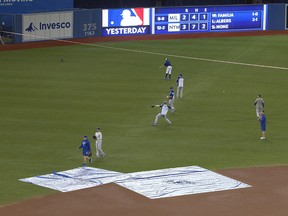 Kansas City Royals players throw in front of tarps protecting the Rogers's Centre field from water coming through the roof on Monday April 16, 2018. (THE CANADIAN PRESS/Fred Thornhill)