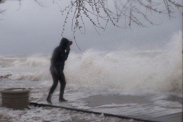 A woman walks along the boardwalk on Toronto's waterfront as a the city is hit by a storm on Sunday, April 15, 2018. THE CANADIAN PRESS/Chris Young