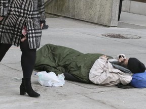A homeless street person sleeps at the corner of Bay and Queen Sts. on Thursday April 5, 2018.