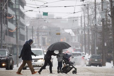 People cross the street as they trudge through falling hail, snow, and rain in Toronto, Ontario on Saturday, April 14, 2018. THE CANADIAN PRESS/Cole Burston