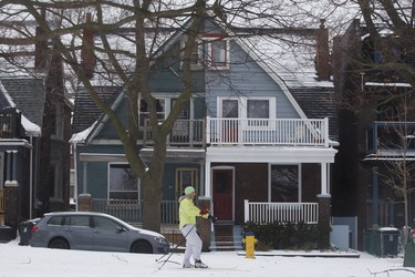 A man cross country skis past houses on the edge of Trinity Bellwoods Park in Toronto, Ontario as a mix of snow, hail, and rain fall on Sunday, April 15. 2018. THE CANADIAN PRESS/Cole Burston