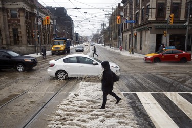 A pedestrian nearly misses getting splashed by a passing car in Toronto, Ontario as a mix of snow, hail, and rain fall on Sunday, April 15. 2018. THE CANADIAN PRESS/Cole Burston