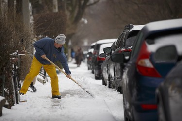 Stefan Randstrom clears ice from his sidewalk in Toronto, Ontario as a mix of snow, hail, and rain fall on Sunday, April 15. 2018. THE CANADIAN PRESS/Cole Burston