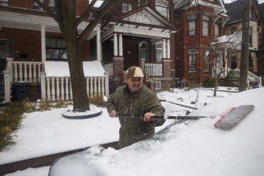 Manuel Carvilho sweeps snow and ice off his car in Toronto, as a mix of snow, hail, and rain fall on Sunday, April 15. 2018. THE CANADIAN PRESS/Cole Burston