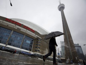 A man walks by the Rogers Centre as reports of falling ice from the CN Tower sparked a closure of parts of the area on Toronto on Monday, April 16, 2018.  THE CANADIAN PRESS/Cole Burston