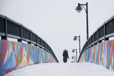 A person trudges through the snow on a pedestrian bridge in Toronto, Ontario as a mix of snow, hail, and rain fall on Saturday, April 14, 2018. THE CANADIAN PRESS/Cole Burston