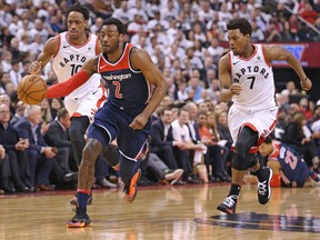John Wall of the Washington Wizards drives the ball between DeMar DeRozan and Kyle Lowry of the Toronto Raptors during Game 2 at the Air Canada Centre on April 17, 2018