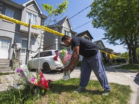 Roger Agada, nephew of the husband of murder victim Rhoderie Estrada, brings flowers to the crime scene. (Ernest Doroszuk, Toronto Sun)