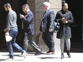 Retired Toronto Police sergeant Angela Costa (with cellphone) leaves a human rights tribunal hearing on Bay St. (Jack Boland, Toronto Sun)