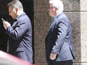 Toronto Police Sgt. Angelo Costa (with cellphone) walks out of a Human Rights Tribunal hearing on Bay St. on May 7, 2018. (Jack Boland, Toronto Sun)