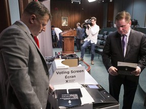Ontario's Chief Electoral Officer Greg Essensa (right) takes a ballot to a vote tabulator as he demonstrates how electronic voting machines will work. (THE CANADIAN PRESS)