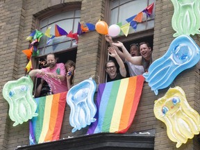 People watch last year’s Pride parade in Toronto from windows. (Craig Robertson/Toronto Sun)