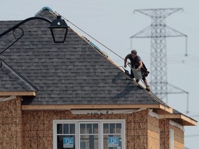 A construction worker shingles the roof of a new home. (THE CANADIAN PRESS)