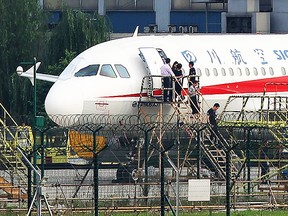 This photo taken on May 14, 2018 shows employees checking a Sichuan Airlines Airbus A319 after an emergency landing, as a broken cockpit window (L) is covered, in Chengdu in China's northwestern Sichuan province. (Getty)
