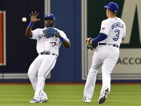 Toronto Blue Jays left fielder Anthony Alford (30) fields the ball after a single off the bat of Boston Red Sox left fielder Andrew Benintendi (16) as Blue Jays shortstop Giovanny Urshela (3) looks on during first inning American League baseball action in Toronto on Saturday, May 12, 2018.