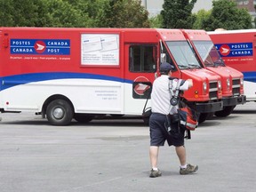 A postal worker walks past Canada Post trucks at a sorting centre. THE CANADIAN PRESS/Ryan Remiorz