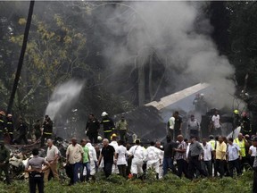 Cuba's President Miguel Diaz-Canel, third from left, walks away from the site where a Boeing 737 plummeted into a yuca field with more than 100 passengers on board, in Havana, Cuba, Friday, May 18, 2018. The Cuban airliner crashed just after takeoff from Havana's international airport on Friday.